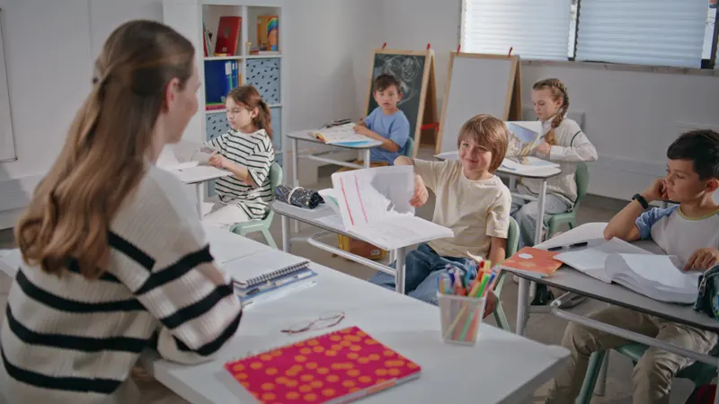 Copii lucrând în bănci într-o sală de clasă luminoasă