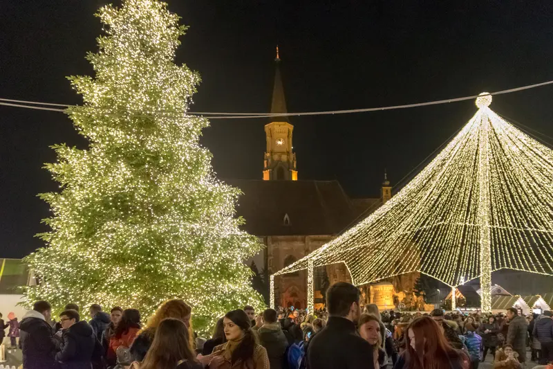 Târgul de Crăciun din Piața Unirii, noaptea: bradul luminat, cortul de lumini și Biserica Sfântul Mihail