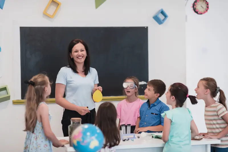 Profesoară ținând un balon în fața unei clase de copii, în timpul unei demonstrații