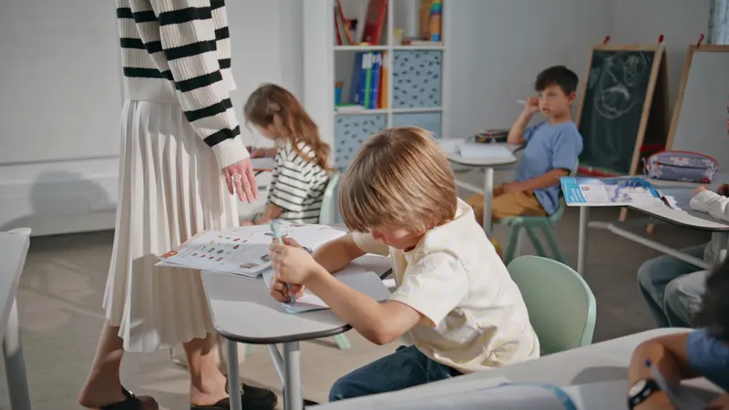 Elev scriind concentrat în bancă, în timpul orei