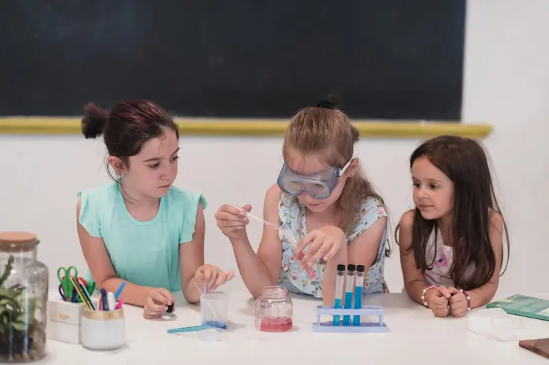 Trei copii lucrând împreună cu eprubete colorate, la un experiment