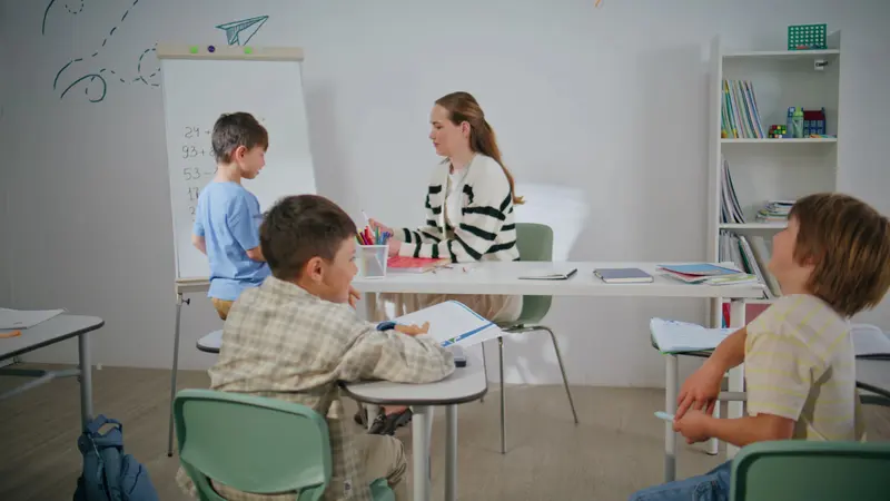 Grup mic de elevi lucrând cu un profesor, într-o sală luminoasă